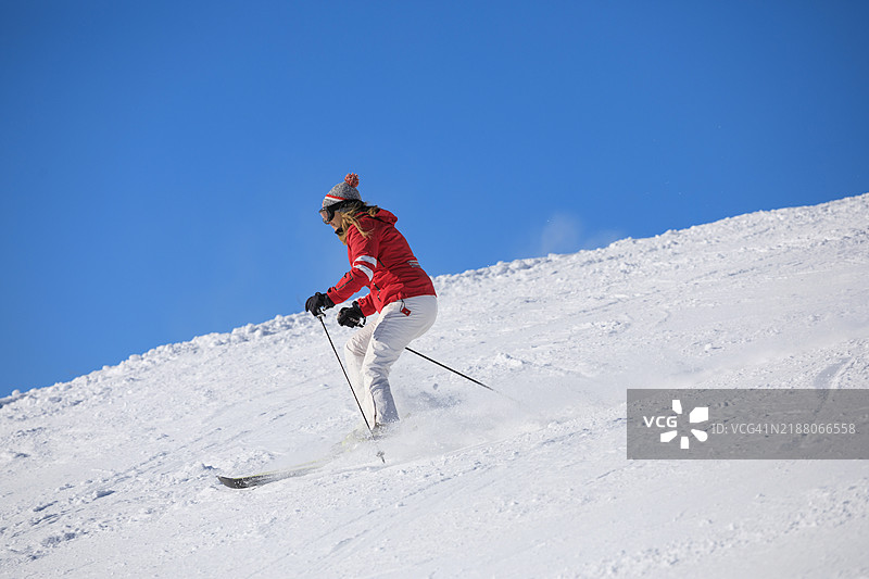 活跃的生活方式，充满活力的女性滑雪者在完美的滑雪坡道上高速滑行，享受阳光明媚的塞拉隆达滑雪度假区。多洛米蒂超级滑雪区的雪山。意大利瓦尔加尔德纳滑雪度假村。图片素材