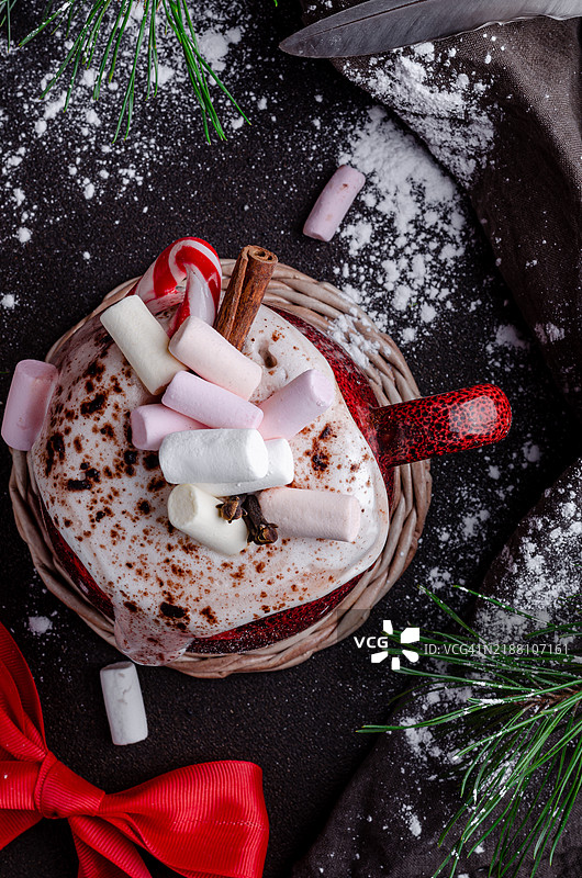 一个温馨的节日场景，展示了一杯热可可，上面放着棉花糖和肉桂棒。图片素材
