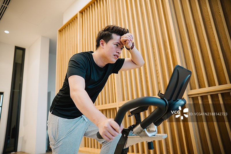 亚洲男子在健身自行车上。图片素材
