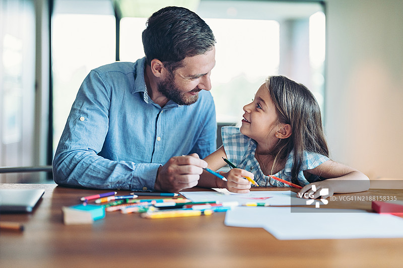 小女孩和她的父亲在家里快乐地进行色彩丰富的绘画活动图片素材