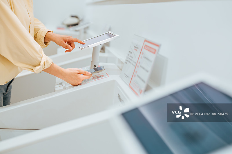 亚洲成熟的女性在服装店用智能手机付款的特写镜头。使用手机扫描二维码付款（二维码是我自己制作的，没有实际交易信息）。图片素材