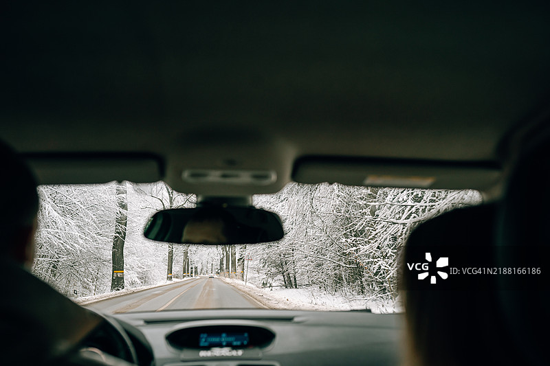 冬季公路旅行：沿着雪-covered道路的假期旅行。汽车视角图片素材