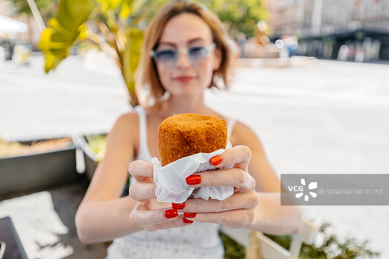 中年女性在西西里卡塔尼亚的一家街边咖啡馆享用阿兰奇尼图片素材