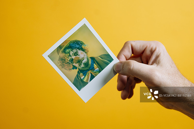 悲伤的小丑照片，背景为鲜艳的黄色。图片素材