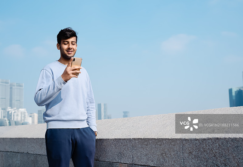 亚洲男子在现代城市环境中看手机图片素材