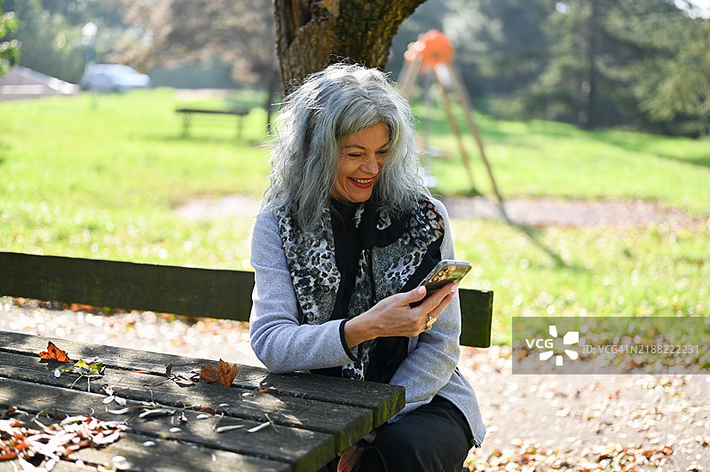 公园长椅上坐着一位灰发女性的肖像。图片素材