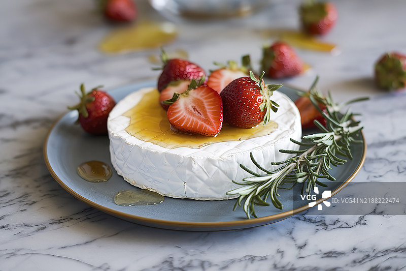 一盘布里奶酪，上面放着草莓，并淋上蜂蜜图片素材