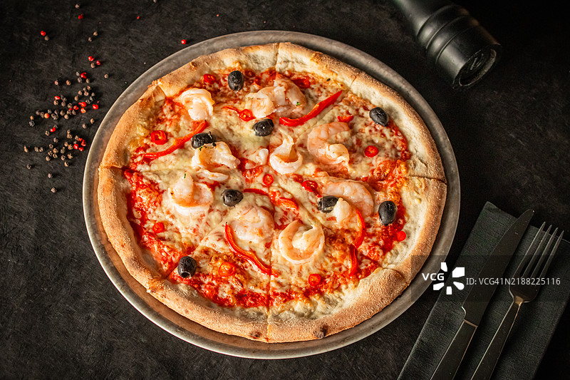 海鲜披萨，上面放有虾、黑橄榄、红辣椒和甜椒图片素材
