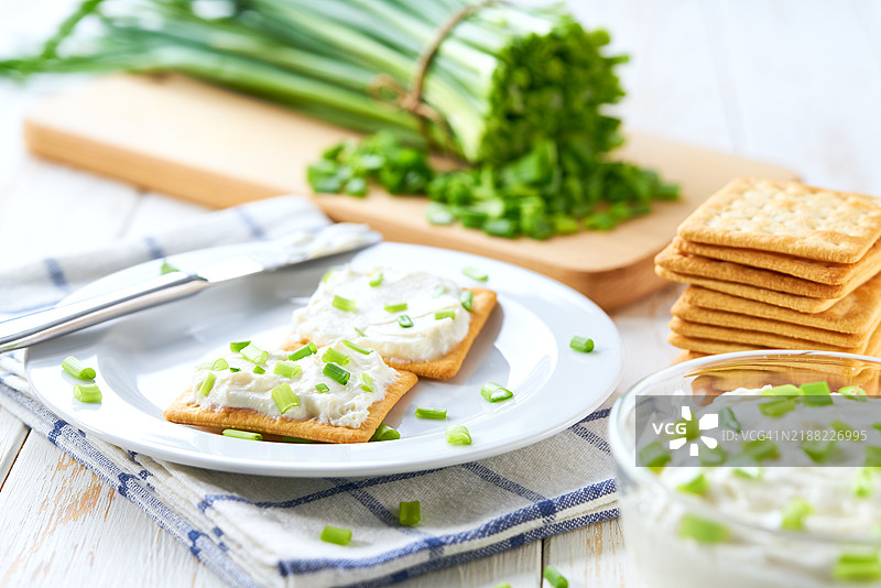 木制砧板上的奶油奶酪和青葱饼干特写 健康早餐概念图片素材