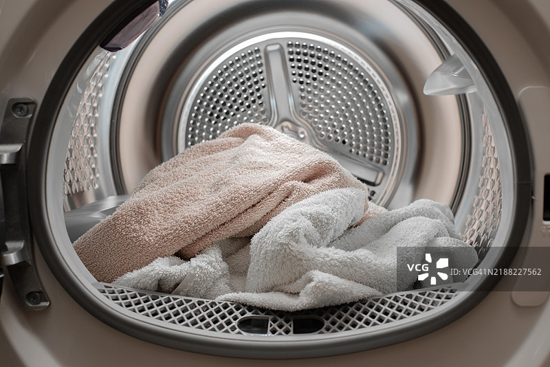 干衣机特写，里面放着洗过和烘干的毛巾，门开着。图片素材