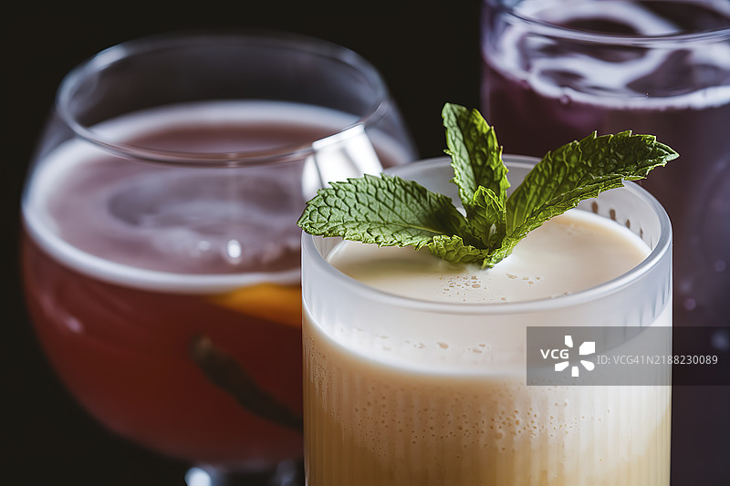 一张特写照片，展示了一杯冰霜覆盖的玻璃，里面装着奶油白色的果汁，上面点缀着一片绿色薄荷叶。图片素材