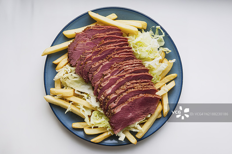 一盘薯条，上面放有切片的熏牛肉和切碎的卷心菜图片素材