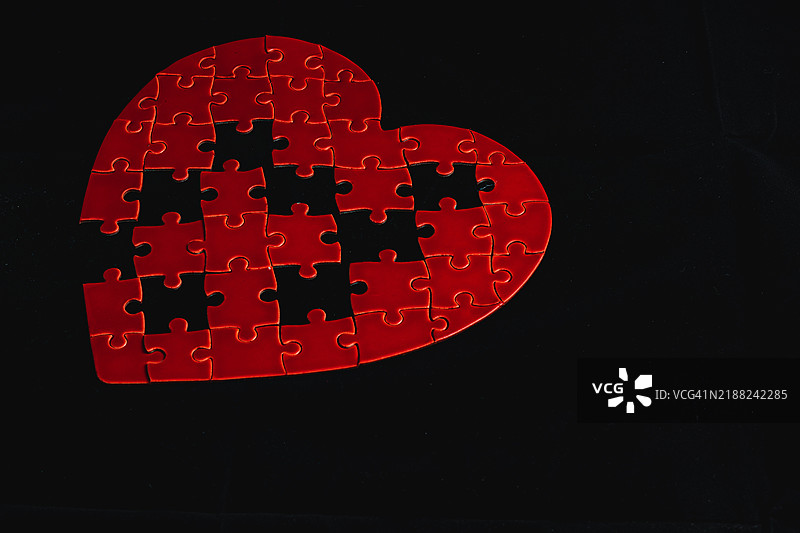 情感概念拼图中的缺失部分，黑色背景上的破碎爱情图片素材