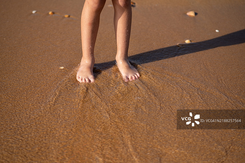 女孩在沙滩和海水之间行走的脚部特写图片素材