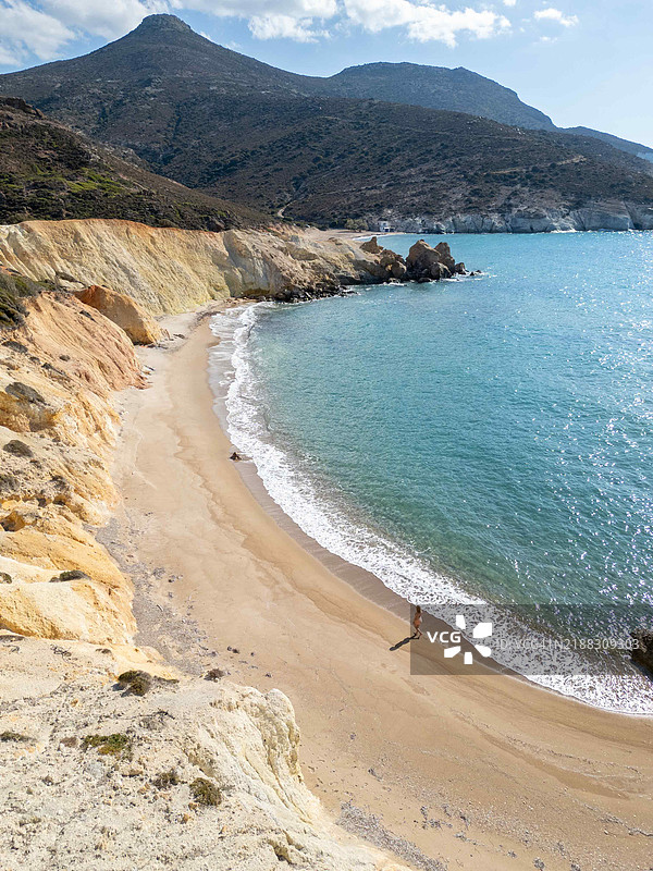 米洛斯的阿吉奥斯·约安尼斯海滩上，年轻女性在沙滩上漫步的鸟瞰图图片素材