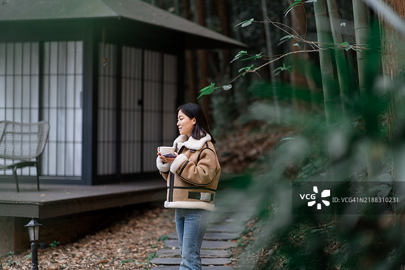 在竹林中手持咖啡杯的亚洲女性图片素材