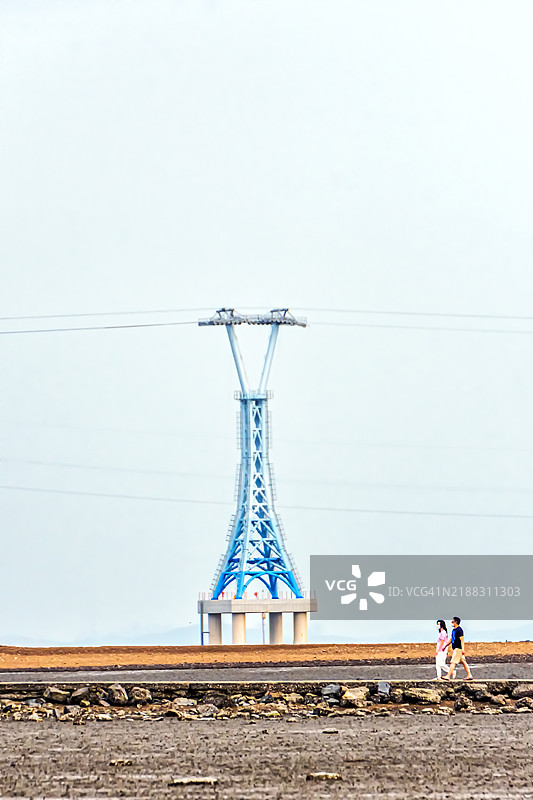 荒凉景观中的输电塔与两个人在行走图片素材