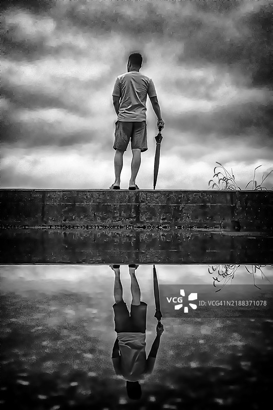 阴天墙上的撑伞男子图片素材