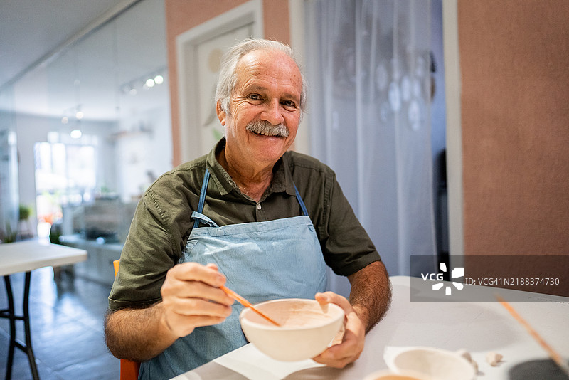 一位老年男子在工作室里作画的肖像图片素材