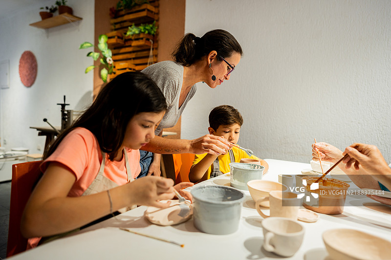 成熟的女性在工作室教授学生陶艺课程图片素材