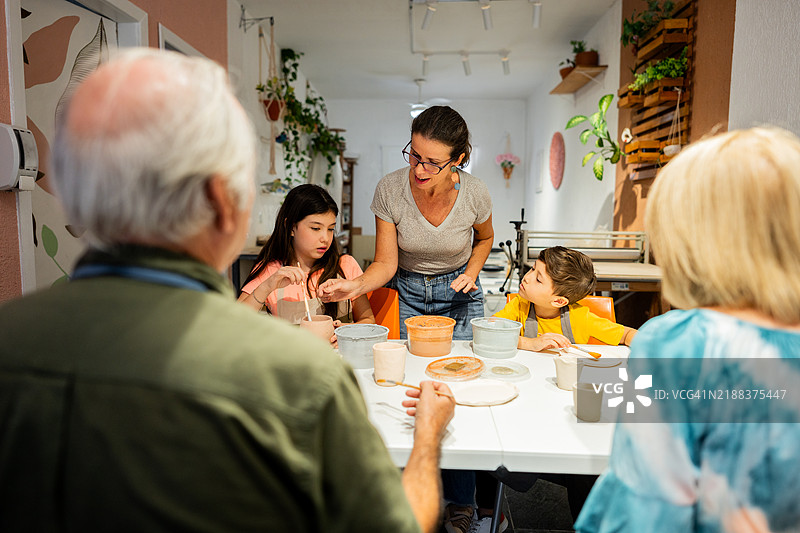 成熟的女性在工作室教授学生陶艺课程图片素材