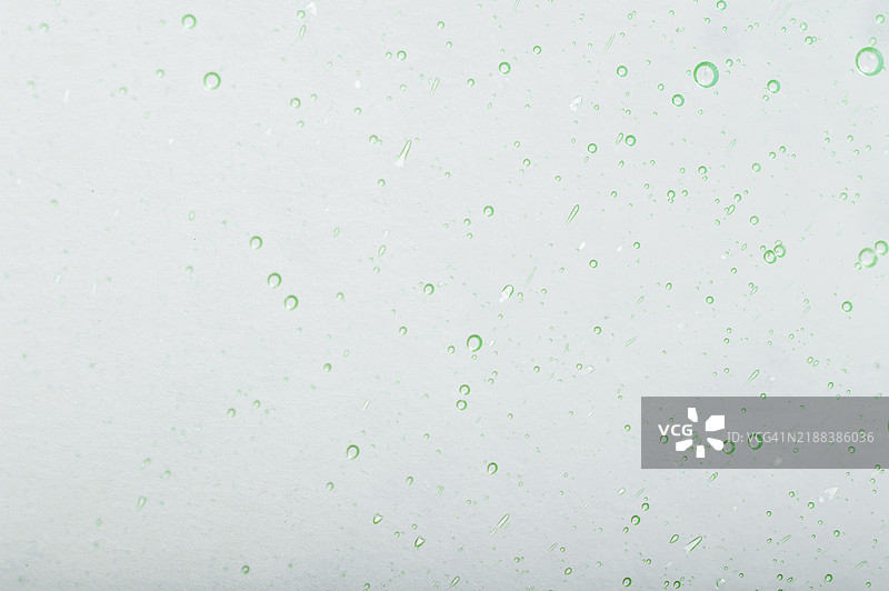 透明表面上的绿色气泡与浅色背景图片素材