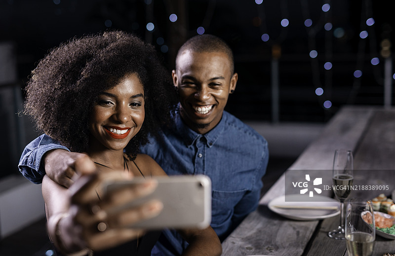 快乐的情侣在现代餐厅享受寿司晚餐，温馨的氛围中一起自拍记录这个特别的时刻图片素材