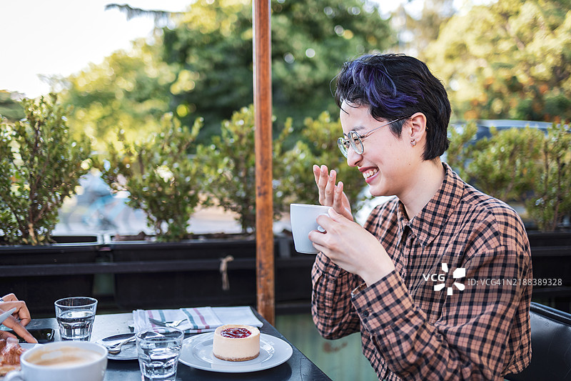 微笑的人在舒适的户外咖啡馆享受咖啡图片素材