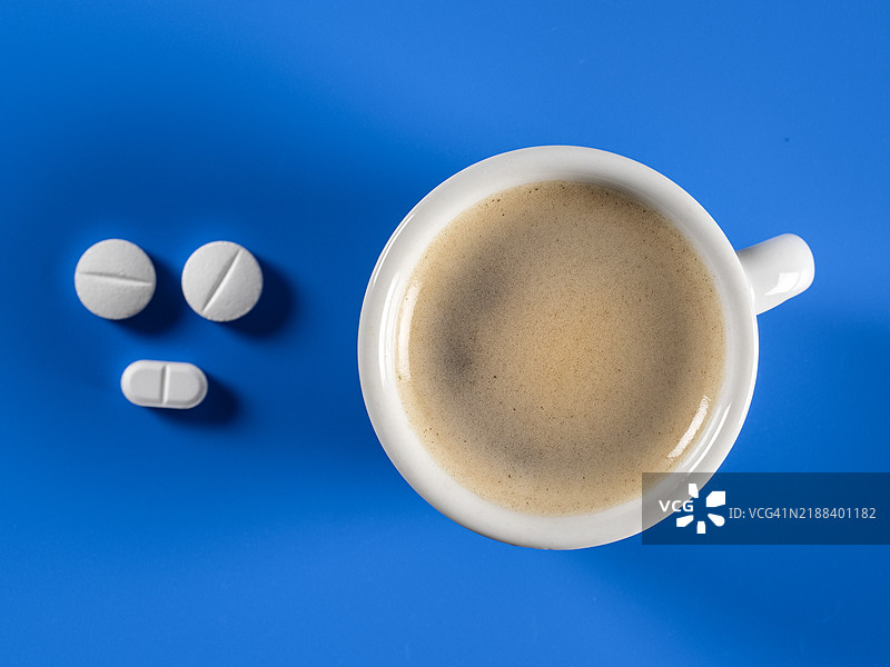 蓝色背景上的一杯浓缩咖啡和药丸。图片素材