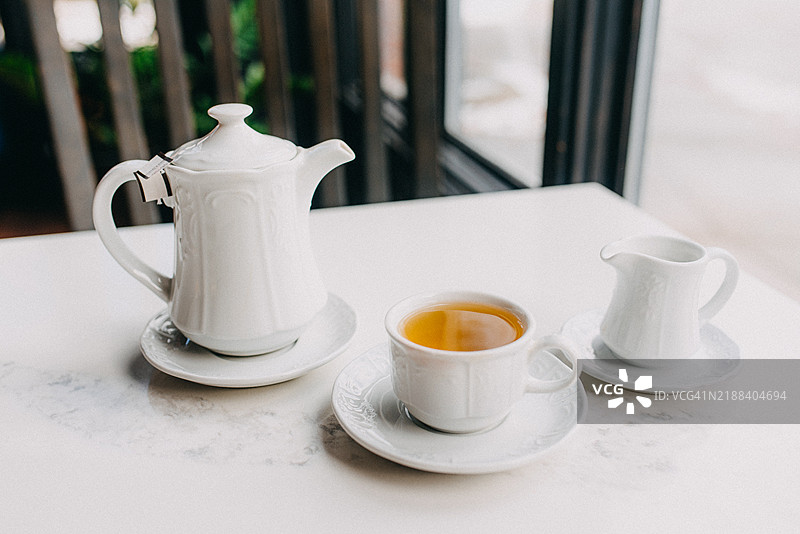 白色配套茶壶、茶杯和牛奶壶放在桌子上图片素材