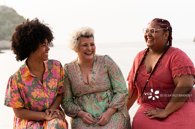 三位快乐的女性在海滩上欢笑在一起图片素材