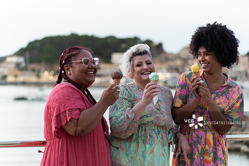 三个快乐的丰满女性在海边吃冰淇淋图片素材
