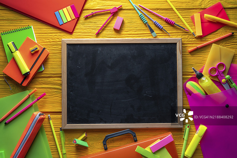 五彩缤纷的霓虹色开学用品在黄色背景的桌子上排列整齐图片素材