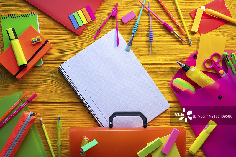 五彩缤纷的霓虹色文具在黄色书桌上的摆放图片素材