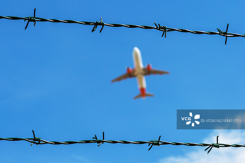 蓝天中有带刺铁丝网和客机图片素材