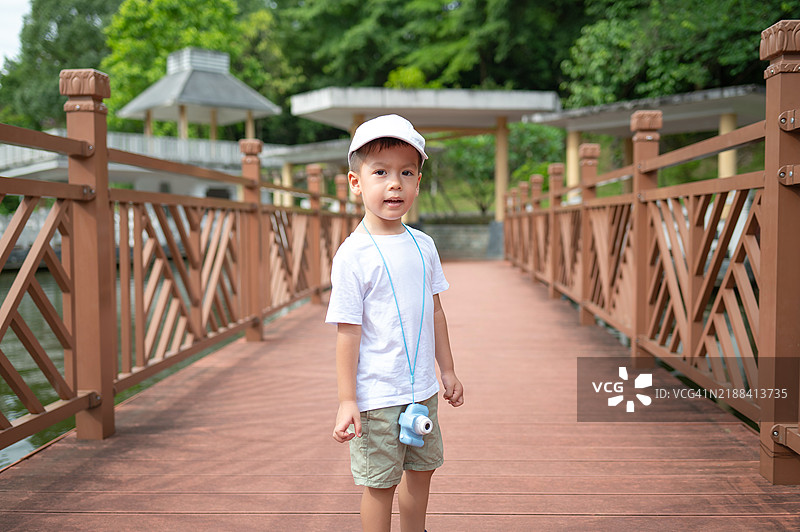 在风景如画的公园里，孩子站在美丽的木桥上图片素材