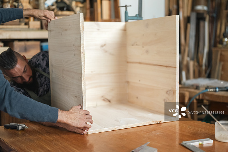 男性木匠正在用木头组装一个木制立方体图片素材