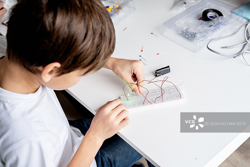 男孩在实验板上使用LED灯进行科学项目。图片素材