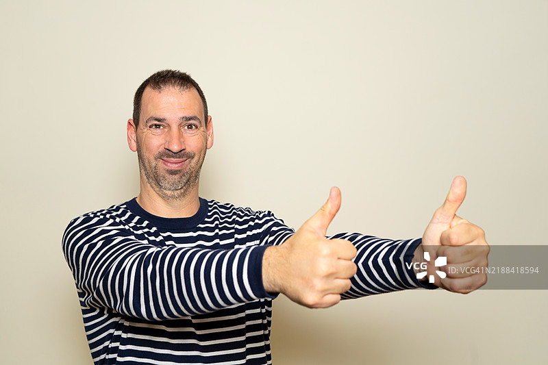 一位40多岁的有胡子的西班牙裔男子穿着条纹毛衣。图片素材