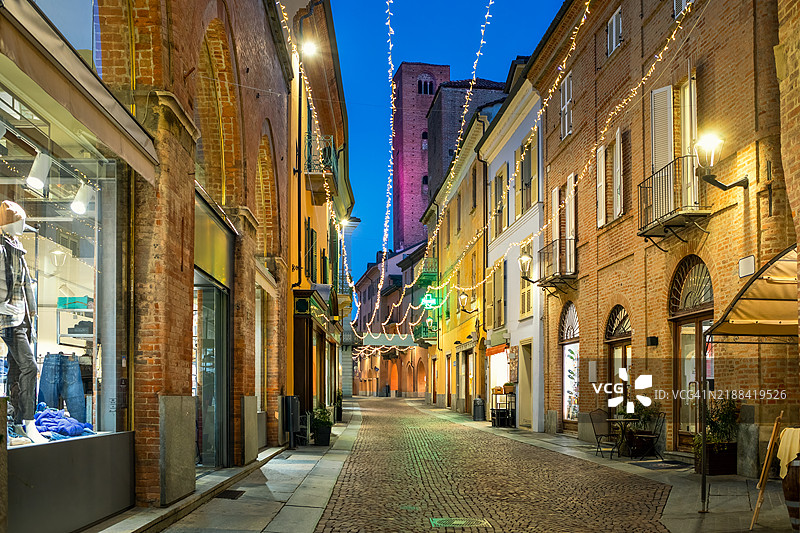 意大利皮埃蒙特阿尔巴的鹅卵石街道和古老建筑在傍晚时分被圣诞灯光照亮图片素材