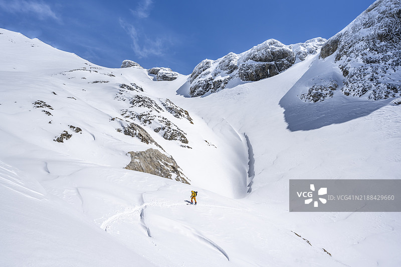 孤独的滑雪旅行者在雪山风景中，攀登到维尔德斯特鲁贝尔小屋，伯尔尼阿尔卑斯山，瑞士，欧洲图片素材