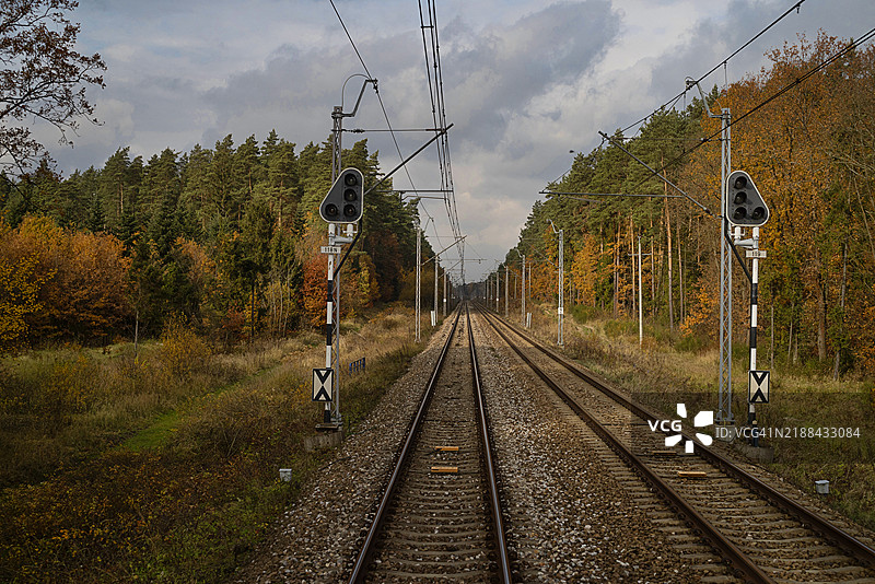波兰秋季色彩中被树木环绕的火车轨道景观。图片素材