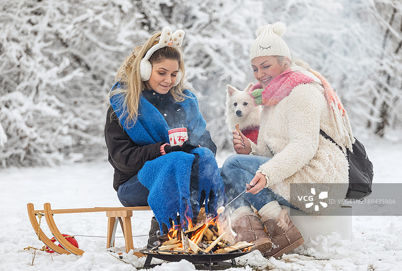 母女俩在篝火旁喝热可可，烤棉花糖图片素材