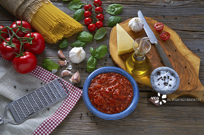 意大利面条配奶酪、番茄、大蒜和罗勒，摆放在木桌上图片素材
