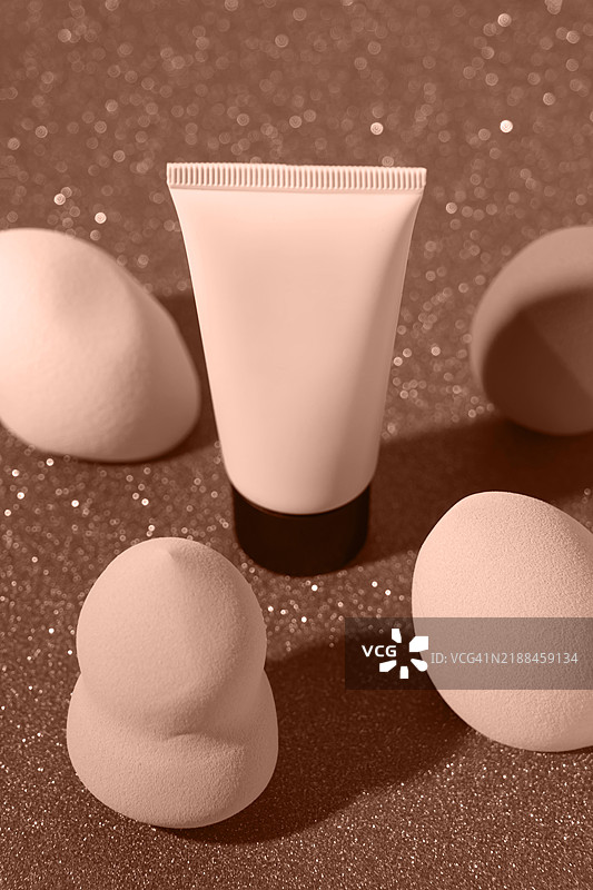 优雅的护肤产品与美容海绵在闪亮的表面上展示。2025年流行色调。摩卡慕斯色样本。图片素材