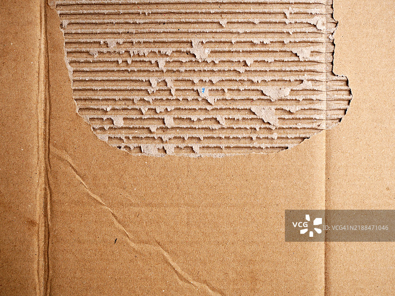 撕裂和折叠的棕色纸箱特写。粗糙的纹理。阳光。自然色彩和光泽。图片素材