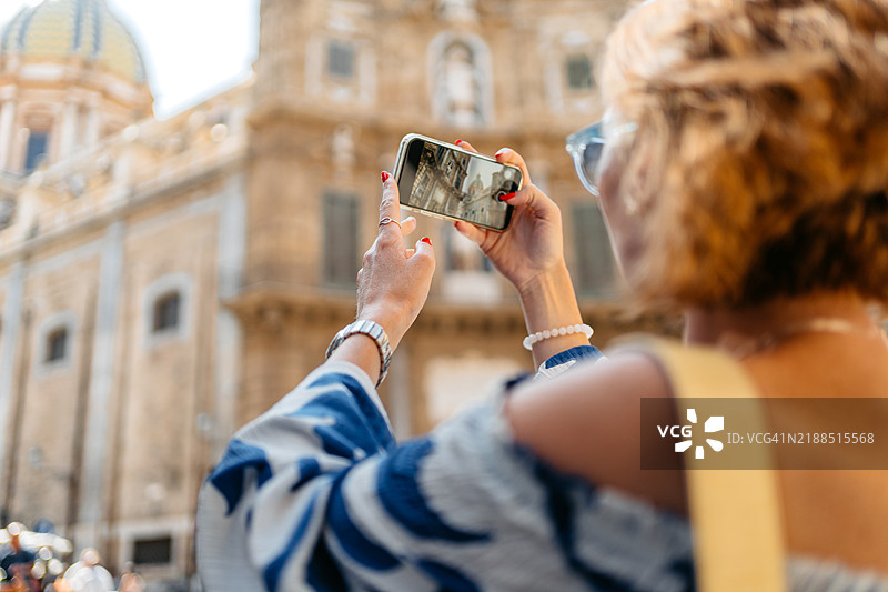 中年女性在西西里岛巴勒莫的四角广场用手机拍照图片素材