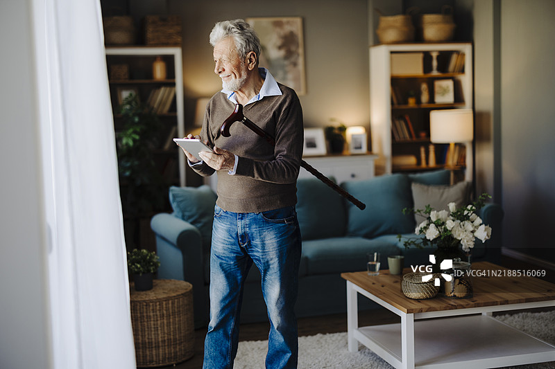 使用手杖的老年男性肖像，正在使用平板电脑图片素材