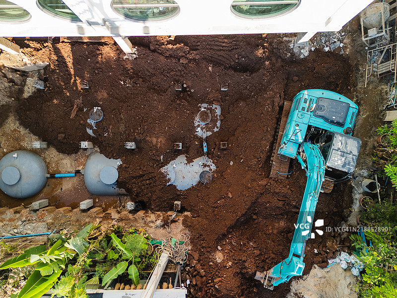 现代建筑附近的挖掘机进行土壤准备的鸟瞰图，水箱和基础工程清晰可见。图片素材