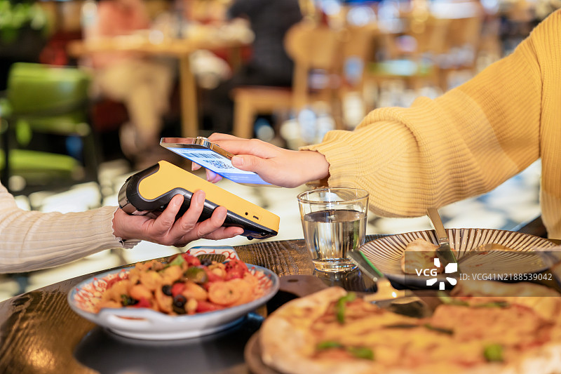 女性手部特写在餐厅用智能手机进行移动支付图片素材